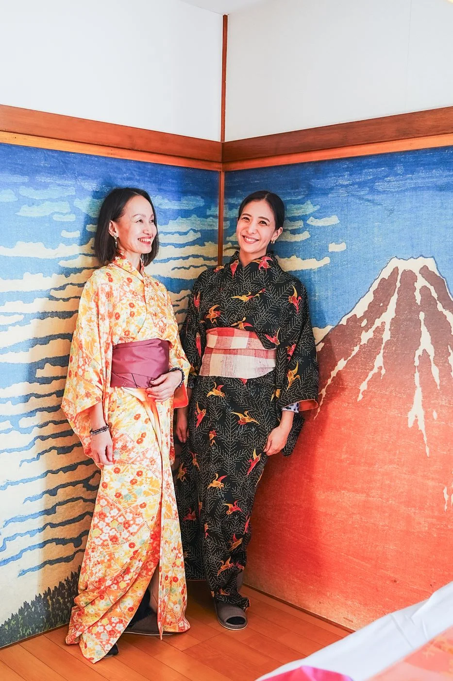 Two guests in kimono in front of the Red Fuji mural
